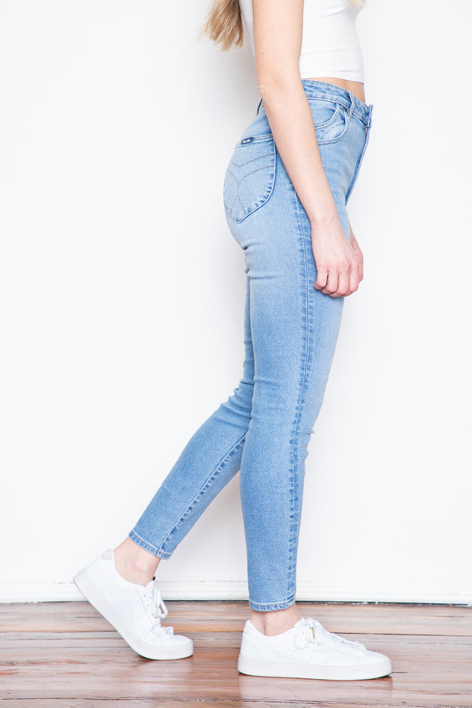 A classic high-rise skinny jean with a slightly cropped inseam and finished in a medium-light indigo colour with fading details. 